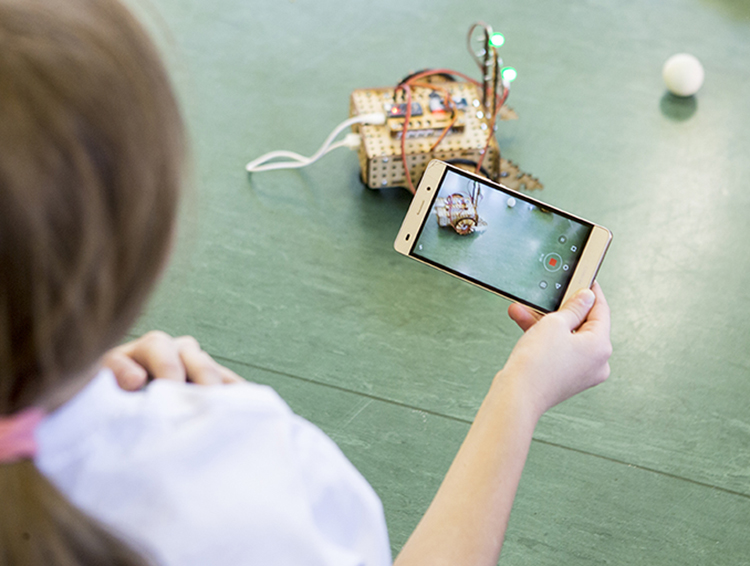 dziewczynka robi zdjęcie robotowi smartfonem. Zajęcia #SuperKoderów. 